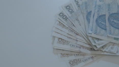 Die-Hand-Eines-Mannes-Legt-Polnische-Zloty-Banknoten-Im-Wert-Von-50-100-200-Scheinen-Auf-Einen-Weißen-Tisch