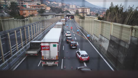 Establisher-tilt-shot-of-heavy-trafficated-Italian-road-at-dusk,-trucks-and-cars