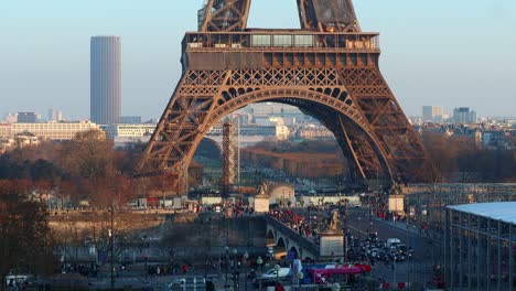 urban-traffic-of-people-and-vehicles-in-the-streets-under-the-eiffel-tower-in-paris,-real-time-shot