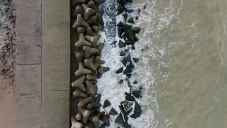 Aerial-establishing-view-of-Port-of-Liepaja-concrete-pier,-Baltic-sea-coastline-day,-big-waves-splashing,-slow-motion-birdseye-drone-shot-moving-forward