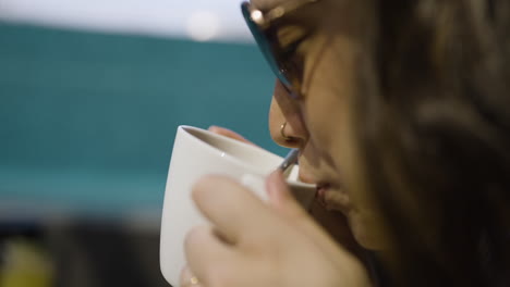 Slow-motion-shot-of-a-beautiful-female-smiling-and-taking-a-drink-of-her-hot-drink