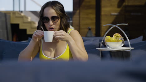 Slow-motion-shot-of-a-woman-in-a-bikini-reaching-for-a-coffee-and-taking-a-drink