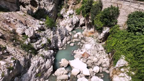 Aerial-shot-of-a-river-flowing-through-rocky-riverbed-in-a-canyon