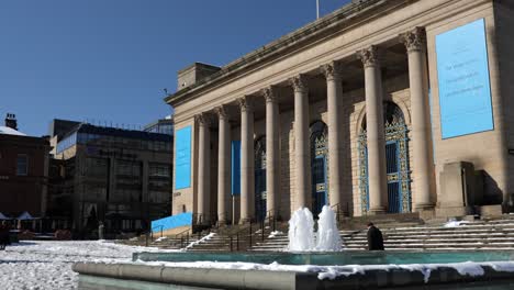 Fountain-water-feature-in-front-of-city-hall-on-a-sunny,-snowy-day,-Sheffield