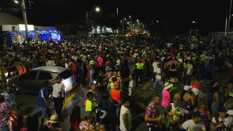 Crowded-streets-celebrating-the-Carnival-of-Barranquilla,-nighttime-in-Colombia---reverse,-drone-shot