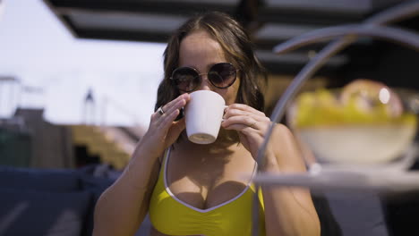 Slow-motion-shot-of-a-happy-attractive-female-in-a-bikini-taking-a-hot-drink