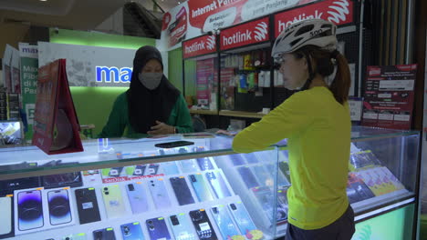 Cyclist-waits-patiently-at-shopping-mall-as-phone-specialist-swaps-sim-cards