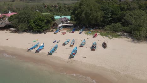 Aerial-orbits-blue-fishing-boats-pulled-onto-Kantiang-beach,-Thailand