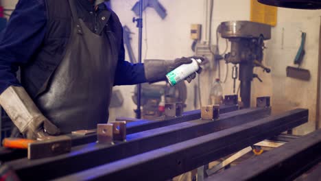 Man-manually-varnishing-in-slow-motion-a-metal-bar-after-welding-it-inside-a-workshop