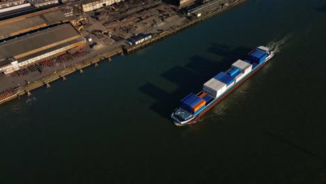 High-angle-aerial-view-of-a-loaded-container-ship-navigating-through-the-canals-of-Ablasserdam,-The-Netherlands