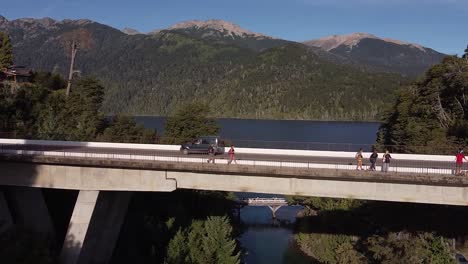Puente-Sobre-El-Rio-Correntoso-Con-El-Lago-Nahuel-Huapi-Y-Las-Montañas-Al-Fondo