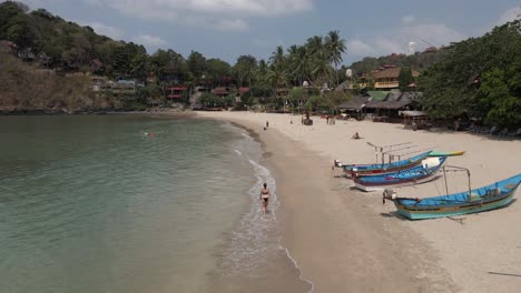 Woman-in-black-bikini-walks-alone-on-sand-beach-on-Koh-Lanta-Thailand