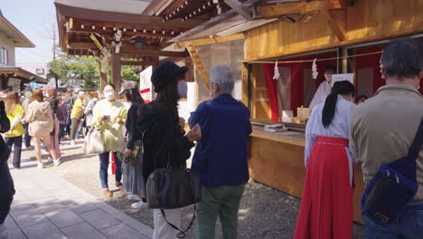 Tourists-Visit-Tagata-Shrine,-Miko-"Shrine-Maiden"-Handing-out-Fortunes