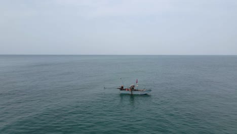 Low-aerial-flyover:-Lone-fisherman-tending-nets-in-small-fishing-boat