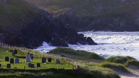 Golden-hour-footage-of-the-cemetary,-waves-and-the-headland-around-Dalmore-beach-near-Carloway