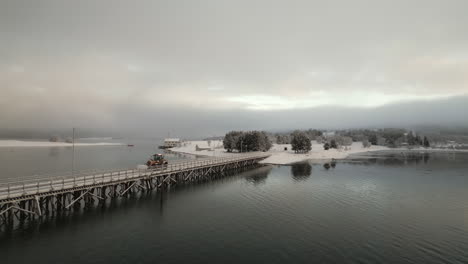 Dozer-crosses-snowy-bridge-over-water-in-Kvaloya,-Arctic-Circle