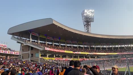 Pan-shot-of-Eden-Gardens-cricket-stadium-crowded-during-a-match-between-India-vs-Sri-Lanka-in-Kolkata,-West-Bengal,-India-with-flood-lights-in-the-background-during-evening-time
