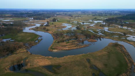 -Drone-flying-around-in-a-circle,-providing-a-unique-perspective-of-the-stunning-natural-scenery-of-flooded-fields-and-a-meandering-river