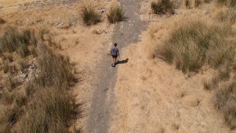 Person-running-through-arid-brown-field-from-aerial-view-with-drone
