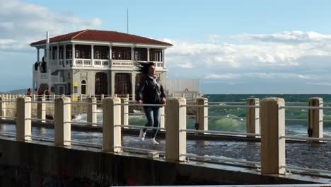 A-middle-aged-Turkish-woman-is-running-away-from-waves-on-the-Historical-Moda-Pier-in-Istanbul-in-slow-motion