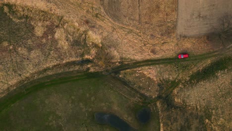 Luftaufnahmen-Der-Landschaft,-Draufsicht-über-Ein-Rotes-Auto,-Das-Auf-Einer-Frühlingswiese-Geparkt-Ist
