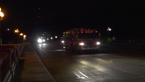 Fire-trucks-drive-down-dimly-lit-street