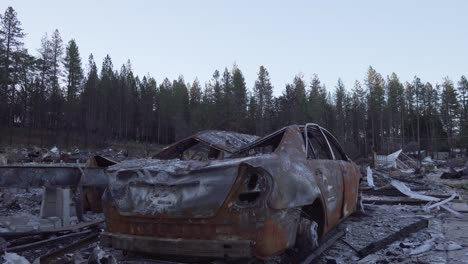 Pan-down-on-burned-car-in-wildfire-aftermath-in-Paradise,-California