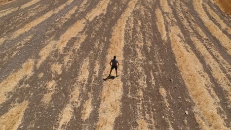 Person-running-through-arid-brown-field-from-aerial-view-with-drone