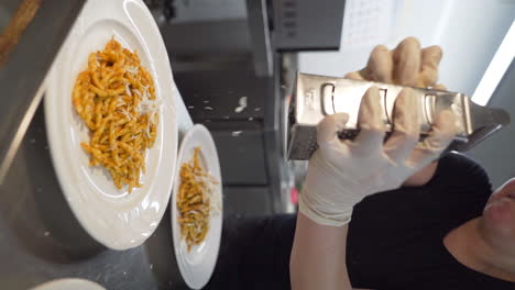 Chef-grating-parmesan-cheese-over-trofie-pasta-dishes-with-tomato-sauce-in-slow-motion