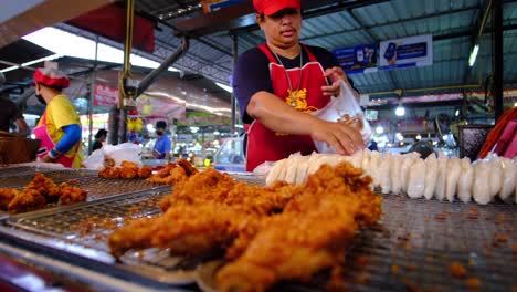 Exhibición-De-Pollo-Frito-Con-Los-Vendedores-En-Un-Mercado-Interior-En-Bangkok,-Tailandia