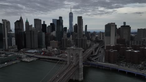 Eine-Luftaufnahme-Der-Brooklyn-Bridge-An-Einem-Bewölkten-Tag-Mit-Lower-Manhattan-Und-Dem-Freedom-Tower-Im-Hintergrund