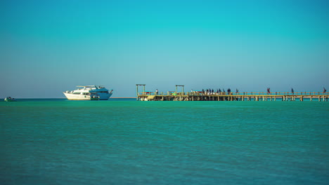 People-gather-on-the-pier-at-Orange-Bay-in-Hurghada,-Egypt---time-lapse-with-yachts-on-the-Red-Sea