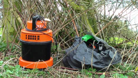 Plastic-bag-full-of-electrical-wires-and-an-orange-piece-of-equipment-fly-tipped-in-the-English-countryside