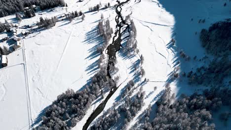 Vista-Aérea-Del-Paisaje-Cubierto-De-Nieve-Con-Bosques-Y-Ríos-En-Un-Soleado-Día-De-Invierno-En-Alp-Grum,-Suiza