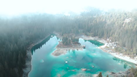 Drone-flying-through-clouds-to-reveal-a-pristine-blue-water-lake-Caumasee-with-forests-around-in-Switzerland