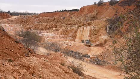 Limestone-quarry-with-loader-excavator-carrying-stone-debris,-Wide-handheld-shot
