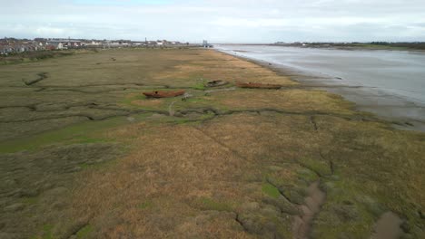 Approaching-rusted-shipwrecks-on-salt-marsh-next-to-River-Wyre-at-Fleetwood-Marshes-Nature-Reserve