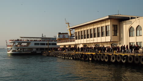 Crowd-of-people-disembarking-from-the-ferry-docking-in-Istanbul-Kadıköy-under-the-warm-sunset-light