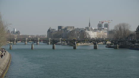 Static-shot-of-people-walking-over-the-ponts-des-arts-in-Paris,-France,-panorama