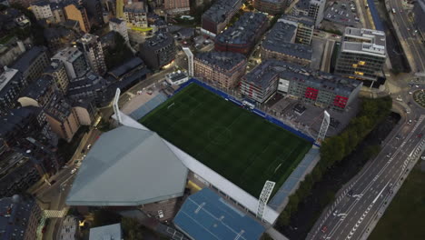 Drone-shot-of-Andorra-la-Vella---drone-is-approaching-a-football-stadium-during-dawn