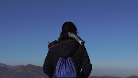 Back-shot-of-a-girl-standing-tall-and-looking-towards-the-mountains-in-the-horizon