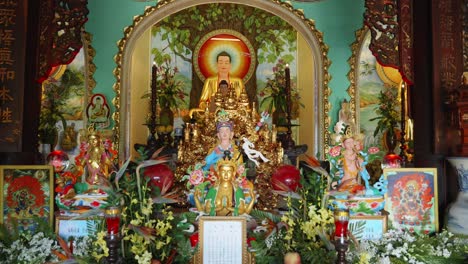 A-colorful-Buddhist-altar-with-multiple-Buddha-figurines,-including-a-large-Buddha-statue-with-an-aureole