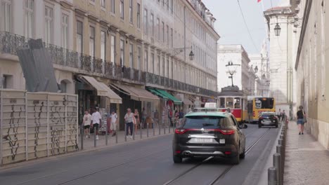 Straßenbahn-Fährt-Entlang-Der-Historischen-Straße-Von-Lissabon,-Mit-Taxis,-Bussen-Und-Personen-Auf-Einem-Motorroller,-Die-Vorbeifahren,-Portugal,-Europa