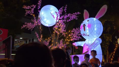 Close-Up-Shot-Of-A-Lit-Up-Carnival-Rabbit-With-Crowds-Of-People-Checking-It-Out