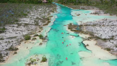 tourists-swimming-in-tropical-blue-Los-Rapidos-rapids-in-Bacalar-Mexico-on-sunny-day,-aerial