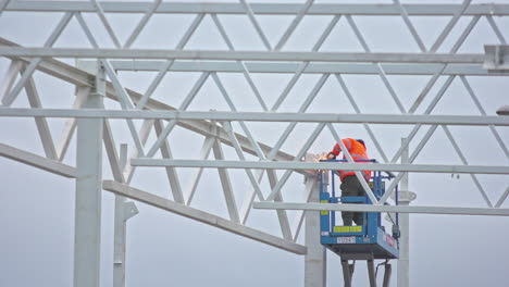 A-worker-welds-a-steel-frame-for-a-construction-from-an-aerial-work-platform