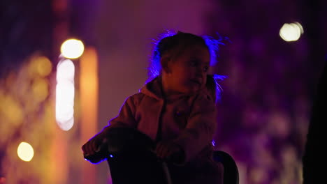 Night-shot-focusing-on-a-little-girl-timidly-riding-in-amusement-park-ride