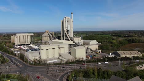 Cement-works-aerial-fly-by-view-from-left-to-right-against-a-background-of-green-fields-and-blue-skies
