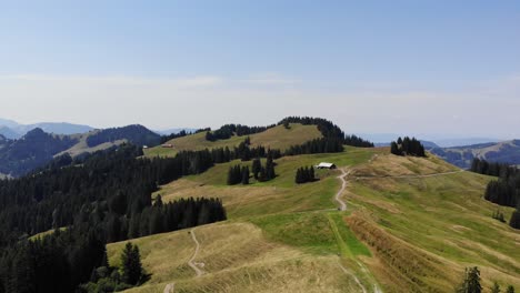 Idyllic-alpine-landscape-cow-barns-on-mountain-pastures-Switzerland-aerial-drone-view
