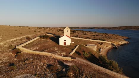 Beautiful-traditional-small-island-church-in-the-Adriatic,-aerial-view-flying-backwards